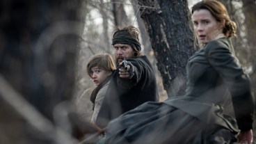 AMERICAN PRIMEVAL. (L to R) Preston Mota as Devin Rowell, Taylor Kitsch as Isaac, and Betty Gilpin as Sara Rowell in Episode 101 of American Primeval.