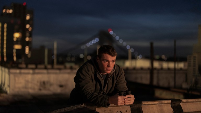 Gabriel Basso as Peter Sutherland, standing on a NYC rooftop in episode 206 of The Night Agent