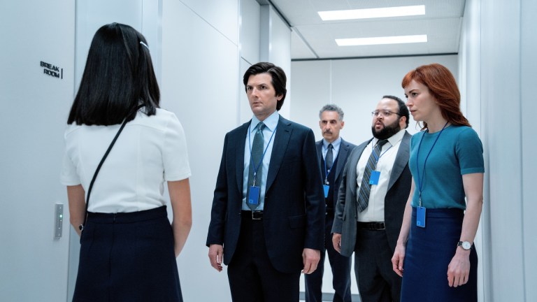 Mark S. (Adam Scott), Irving B. (John Turturro), Dylan G. (Zach Cherry), and Helly R. (Britt Lower) look at Miss Huang (Sarah Bock) in Severance season 2.